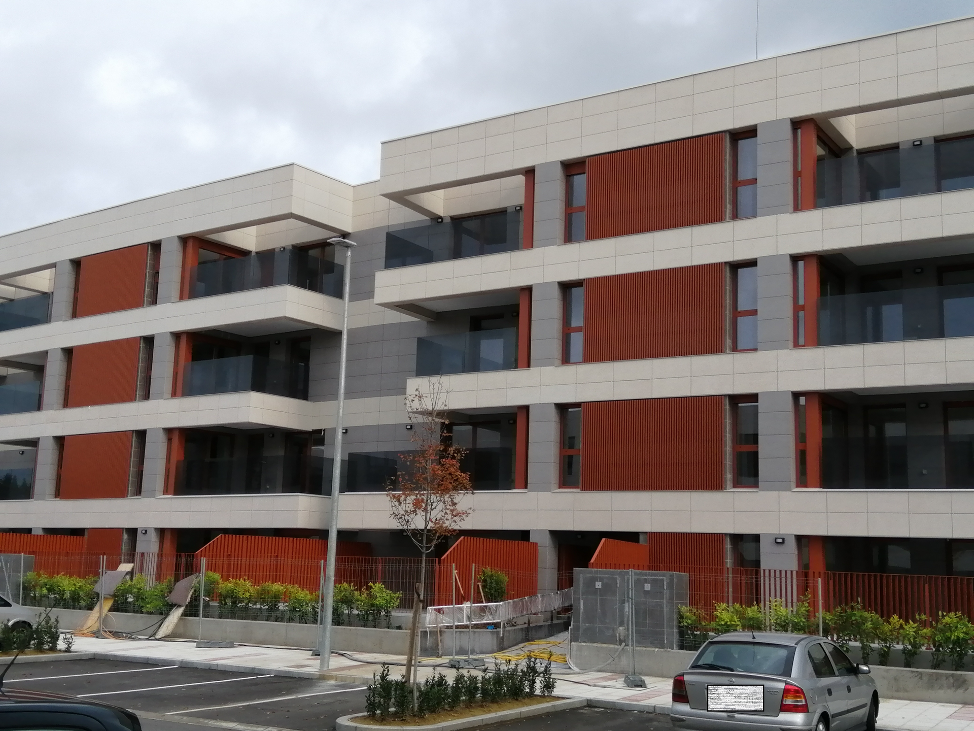 Un coche está aparcado delante de un gran edificio de apartamentos.