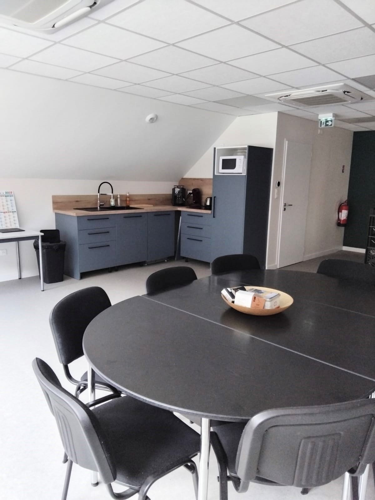 Une petite cuisine de bureau avec une table et des chaises. 