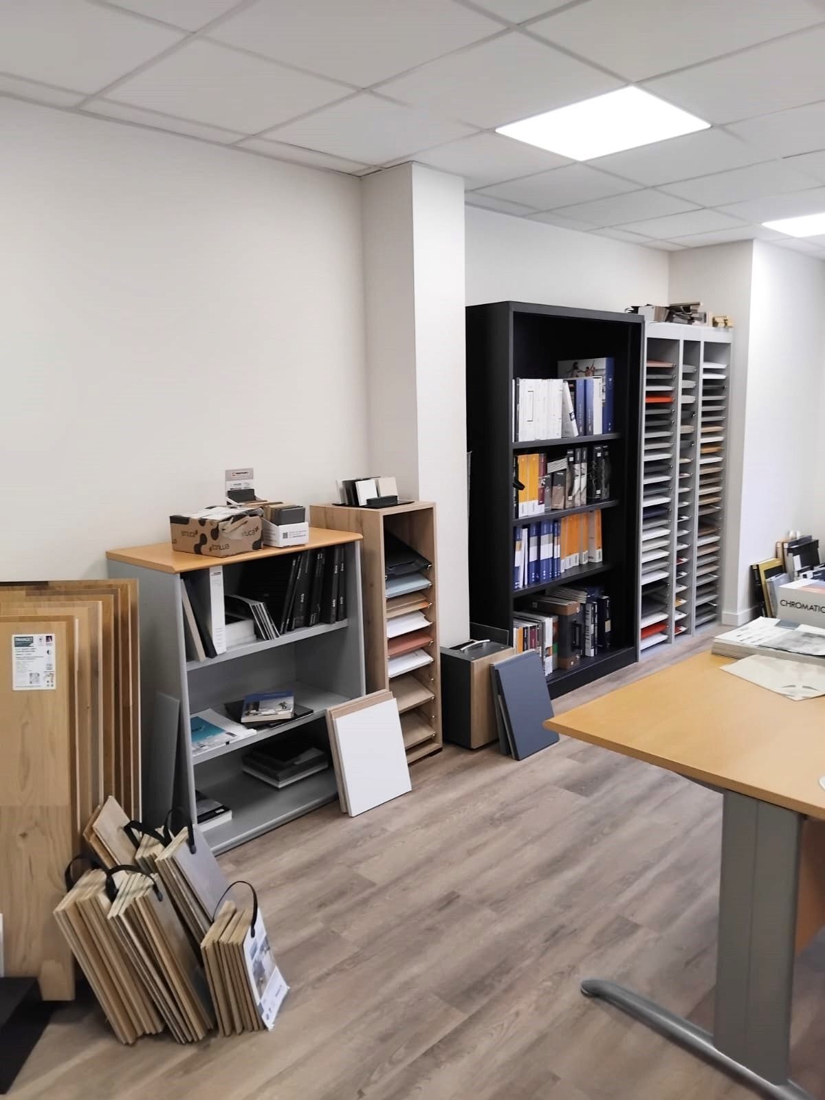Intérieur de bureau avec étagères, bureau et échantillons de matériaux.