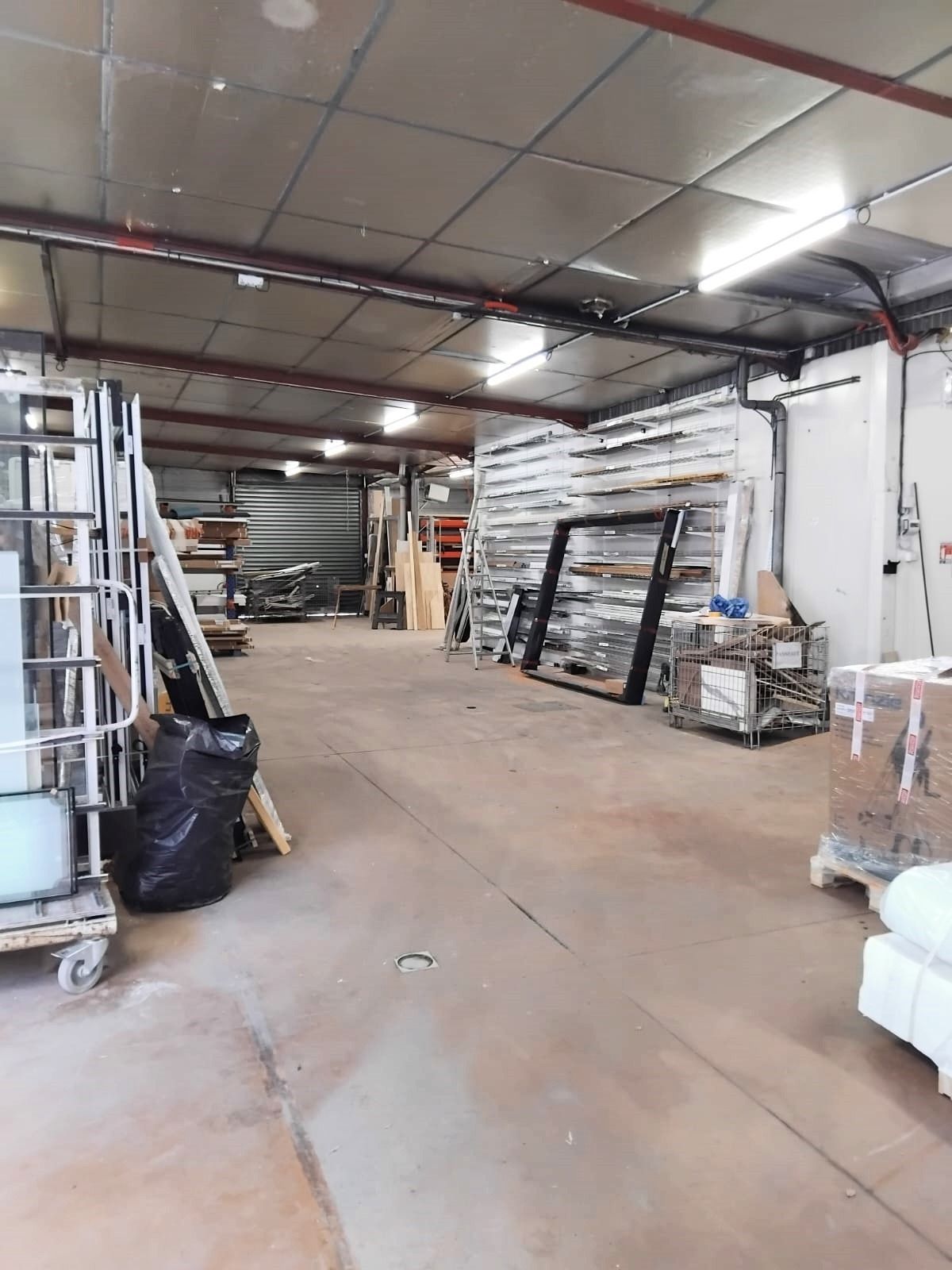 Intérieur d'entrepôt avec charpente métallique, matériaux et équipements.