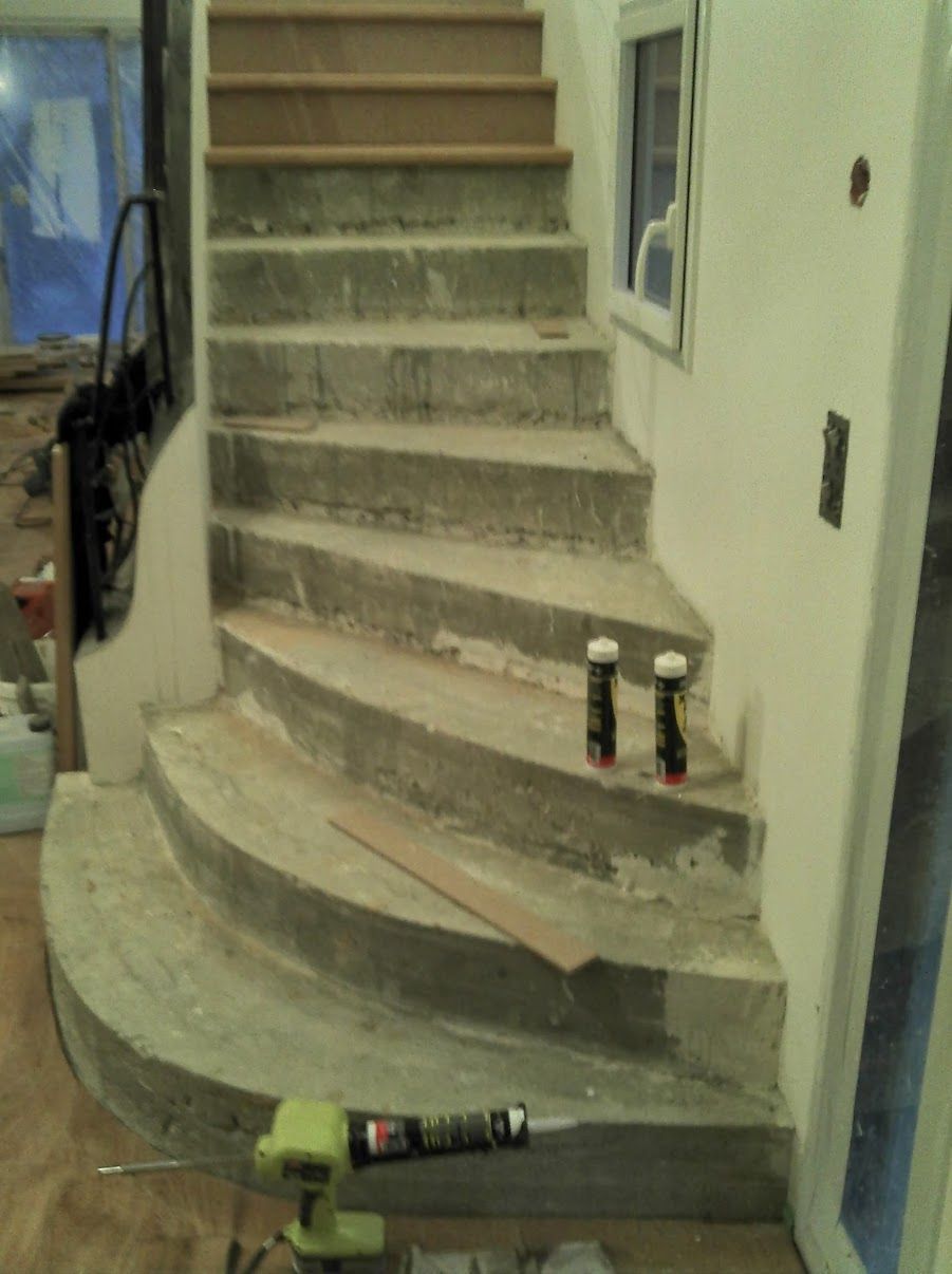 Escalier incurvé en béton avec deux petites bombes aérosol, une perceuse électrique et une planche de bois.