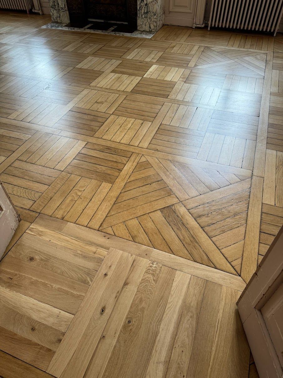 Parquet en bois à motif géométrique, réfléchissant la lumière.