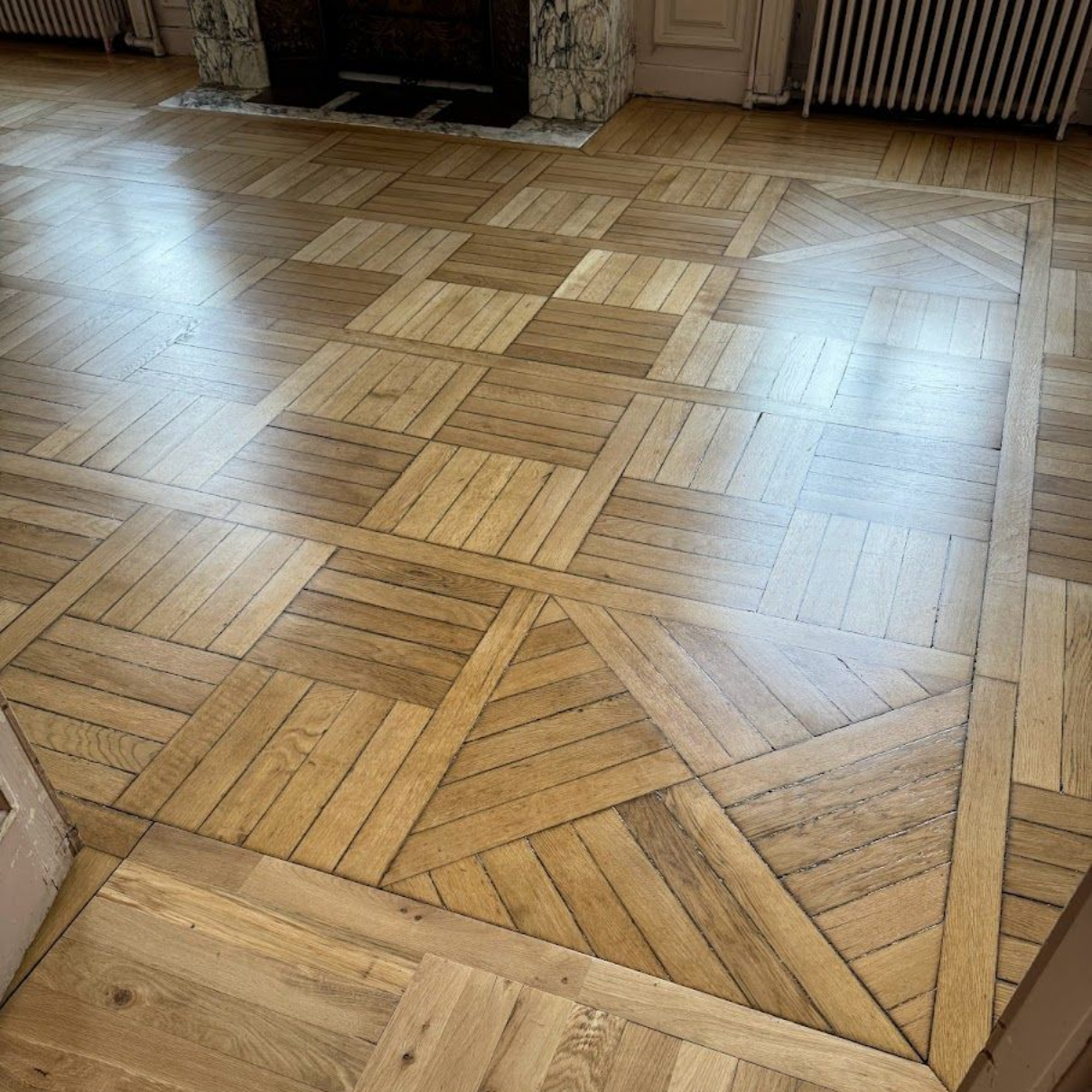 Personne appliquant une finition sur un parquet à l'aide d'une serpillière et d'un seau.