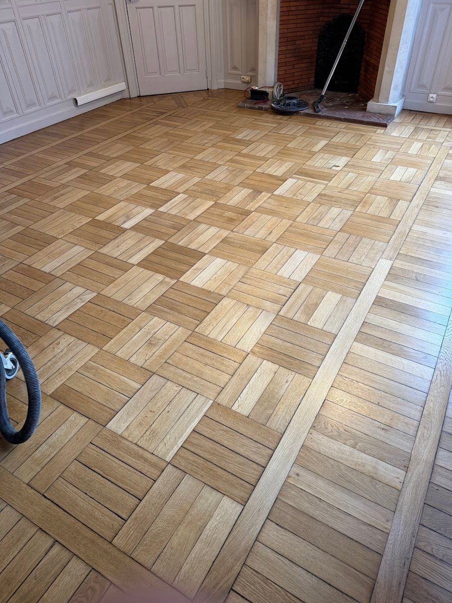 Personne appliquant une finition sur un parquet à l'aide d'une serpillière et d'un seau.