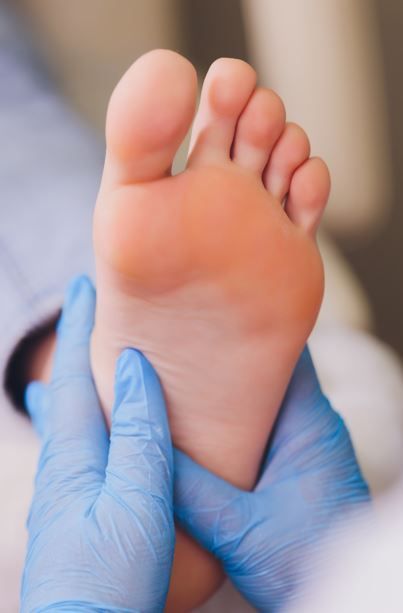 Pie en foco, sostenido por manos enguantadas, examen médico.