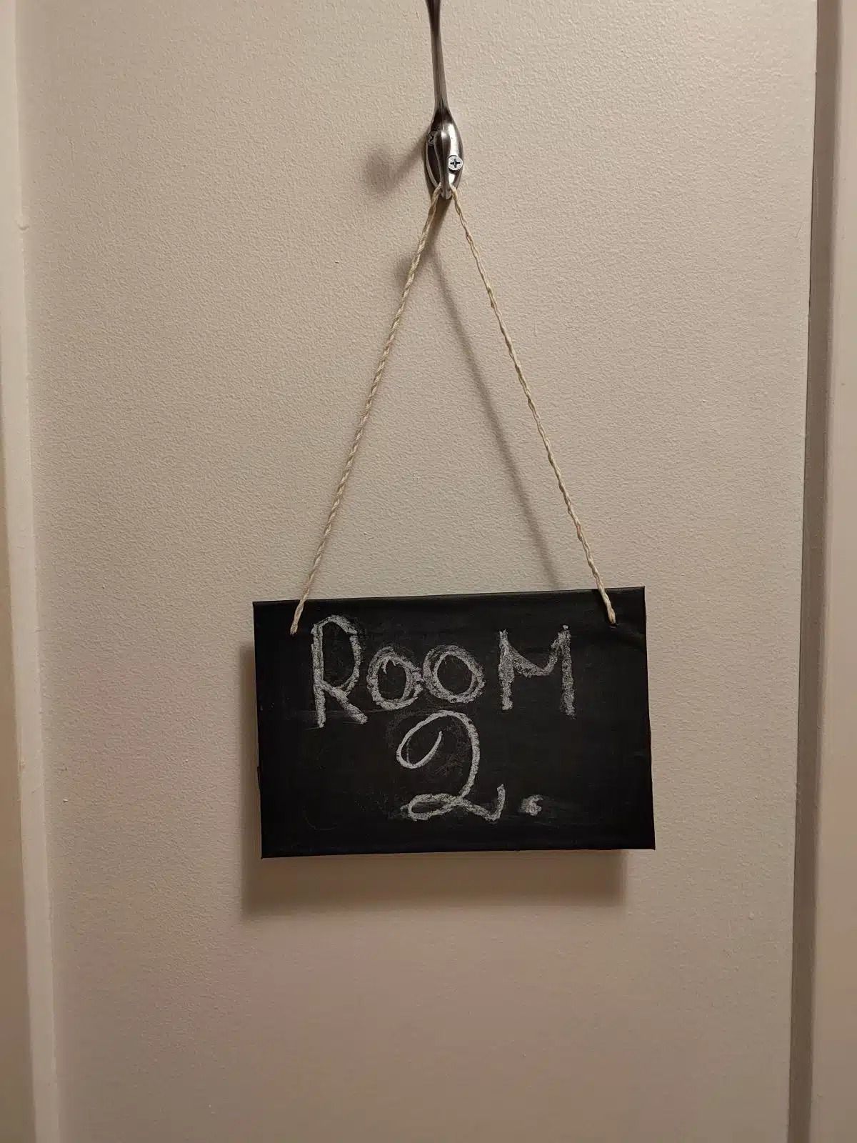 Ovessa roikkuvassa mustassa liitutaulussa lukee ”Huone 21”.