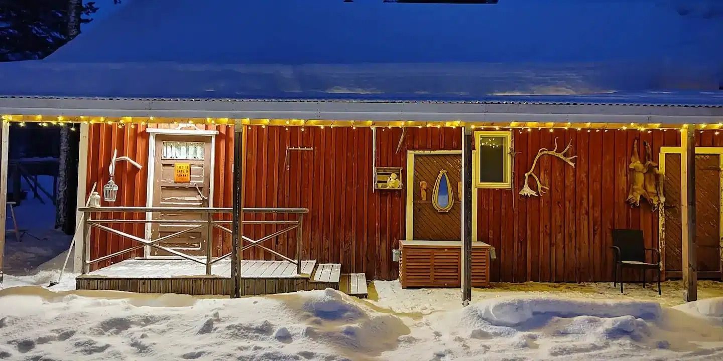 Luminen punainen mökki, jossa lämpimän keltaiset valot hehkuvat hämärässä