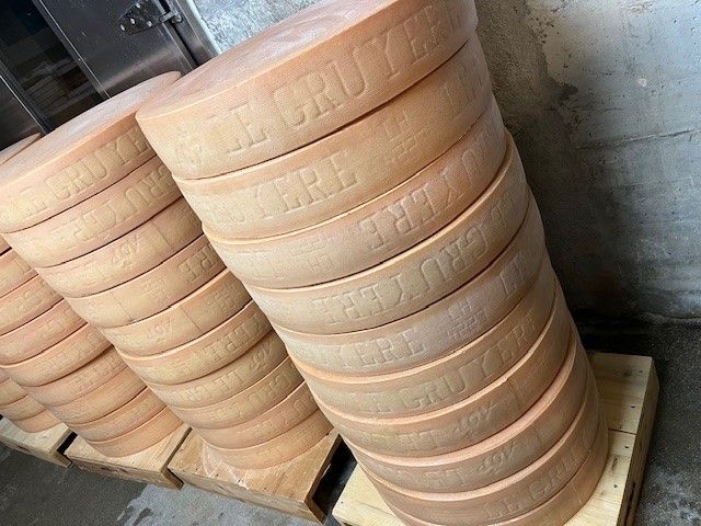 Une pile de meules de fromage superposées sur des palettes en bois.