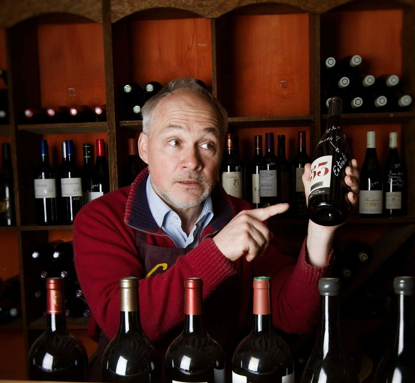 Un caviste tient une bouteille à la main dans sa cave