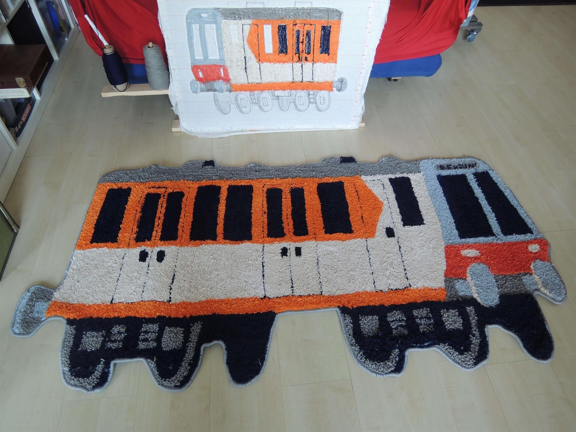 Ein Teppich in Form eines Zuges liegt auf dem Boden