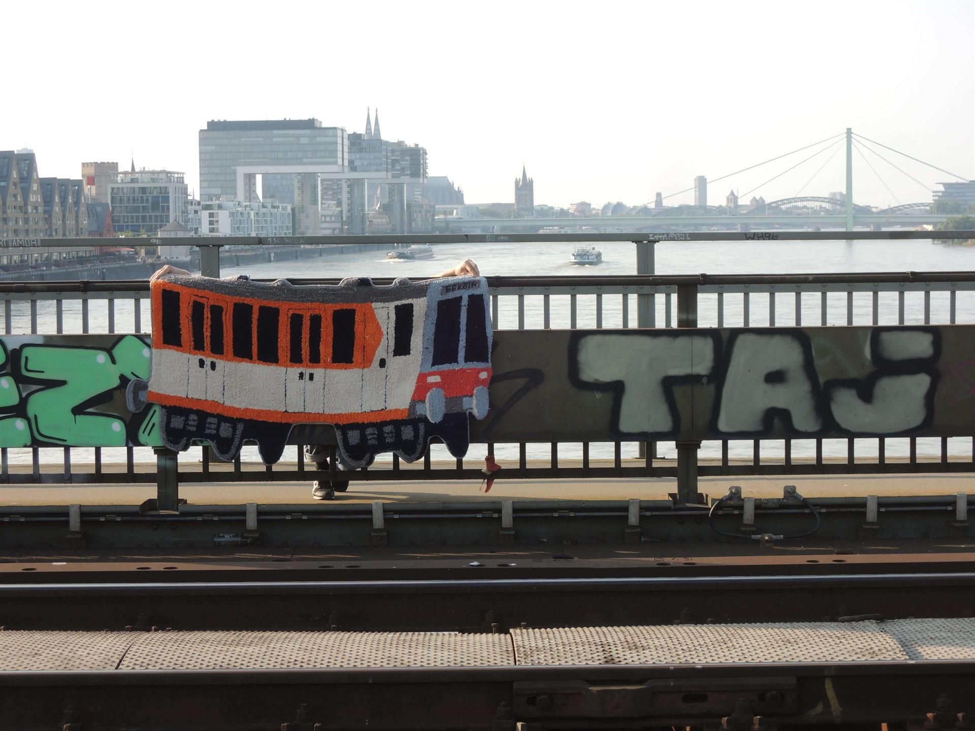 Ein Zug auf einer Brücke mit Graffiti, auf dem steht „Tag“