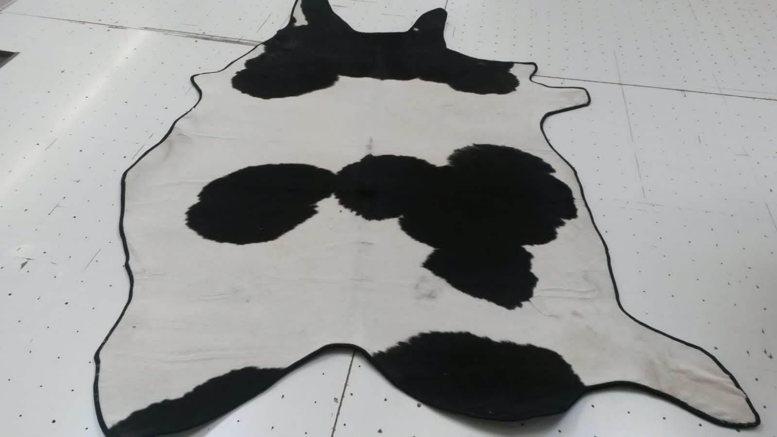 Ein schwarz-weißer Teppich mit Kuhmuster auf weißem Untergrund