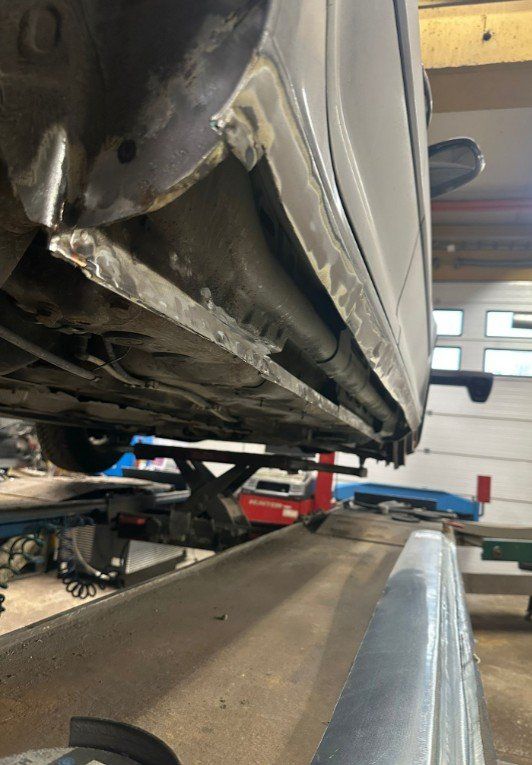 Vaurioitunut musta auton helmapaneeli hississä autokorjaamolla
