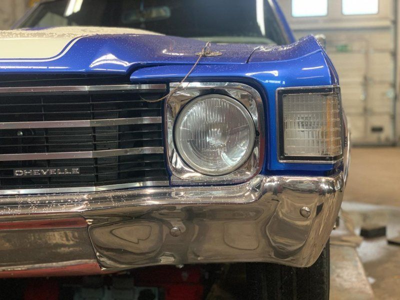 Lähikuva sinisen klassisen Chevrolet-auton keulasta autotallissa, jossa näkyvät etusäleikkö ja ajovalot