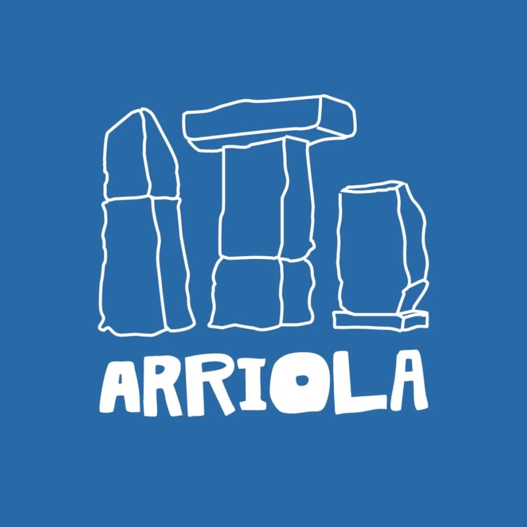Un dibujo lineal blanco de megalitos al estilo de Stonehenge sobre la palabra "ARRIOLA" en una tipograf&iacute;a divertida.
