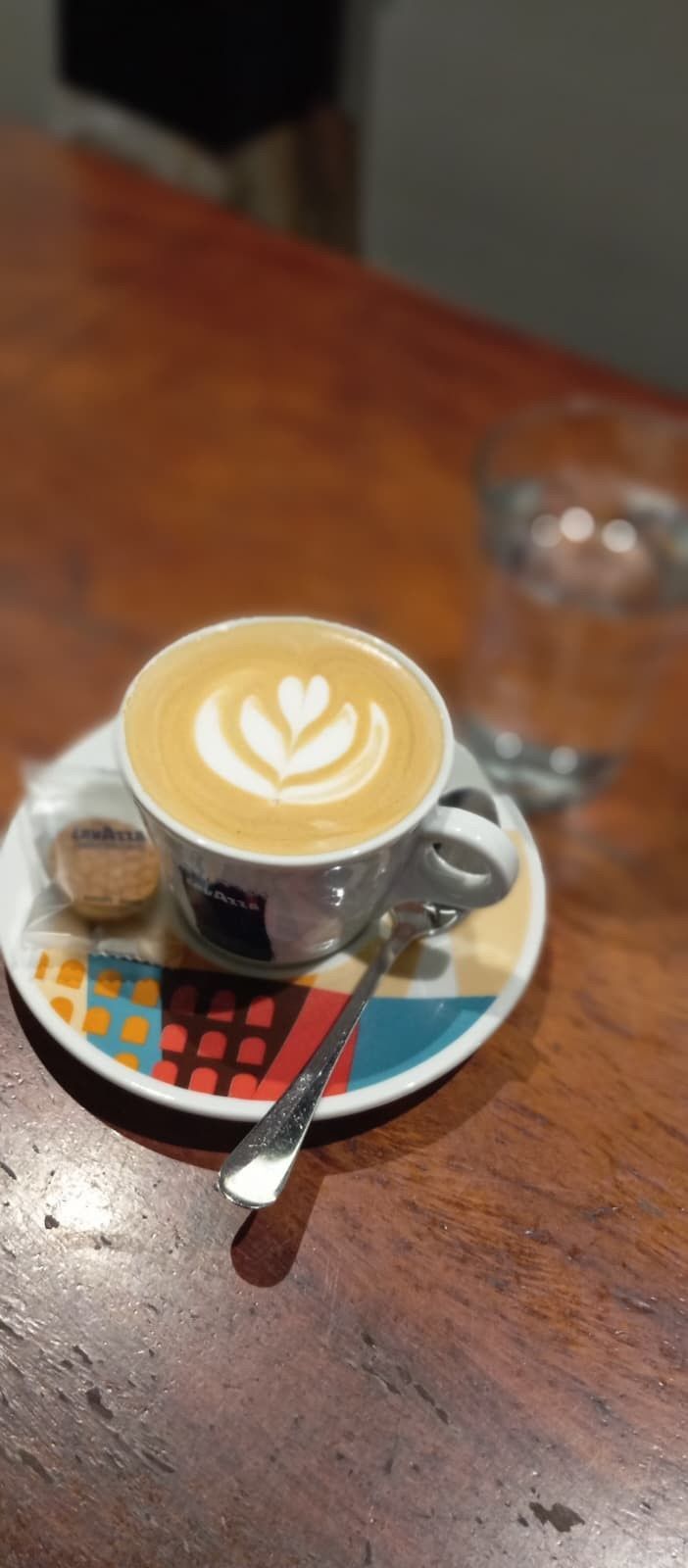 Una hilera de copitas llenas de vino tinto oscuro, dispuestas sobre una tabla de madera en un ambiente con luz tenue.