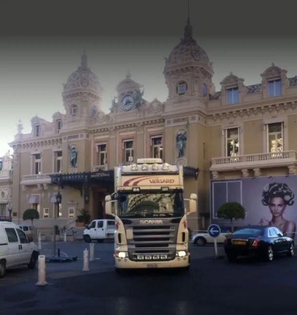 Un camion garé devant un grand bâtiment orné de dômes, de voitures et d'une affiche.
