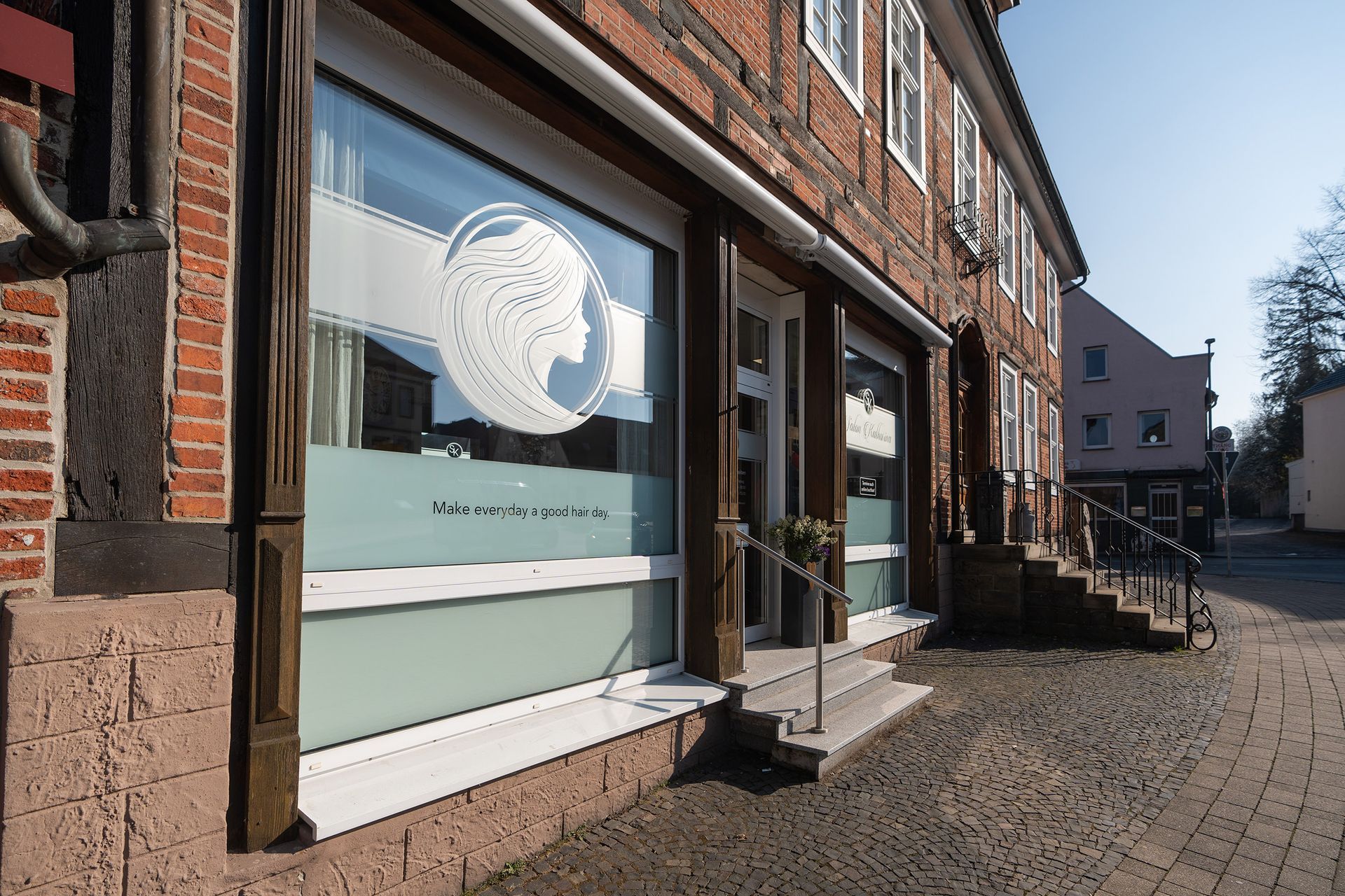 Ein Backsteingebäude mit der Spiegelung eines Frauengesichts im Fenster Salon Katharina 