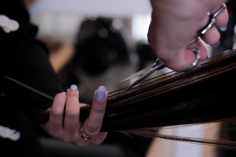 Einer Frau werden von einem Friseur mit einer Schere die Haare geschnitten Salon Katharina 