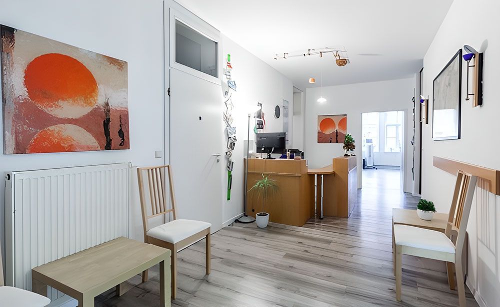 Wartezimmer mit Kunst, Stühlen und Holzboden.