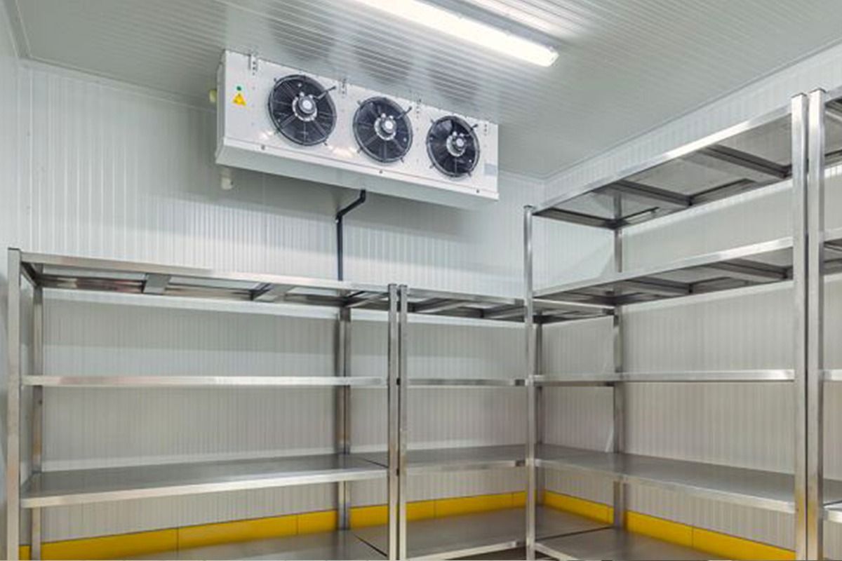 Estanterías vacías de acero inoxidable en el interior de una cámara frigorífica comercial con un evaporador