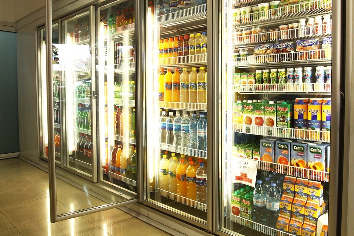 Una vitrina refrigerada bien iluminada en una tienda, con estantes repletos de diversas bebidas embotelladas
