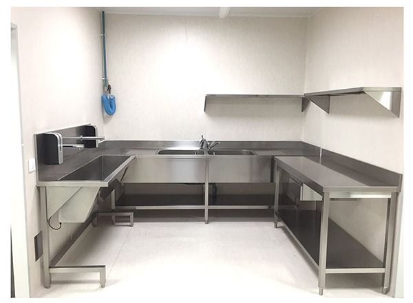 Una cocina industrial de acero inoxidable equipada con fregadero, encimera y estanterías montadas en la pared