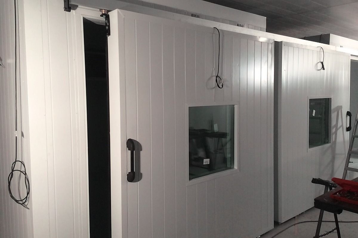 Dos puertas correderas blancas con ventanas rectangulares instaladas sobre un sistema de rieles metálicos