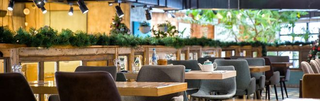 El interior de un restaurante con mesas de madera y sillas de color gris oscuro