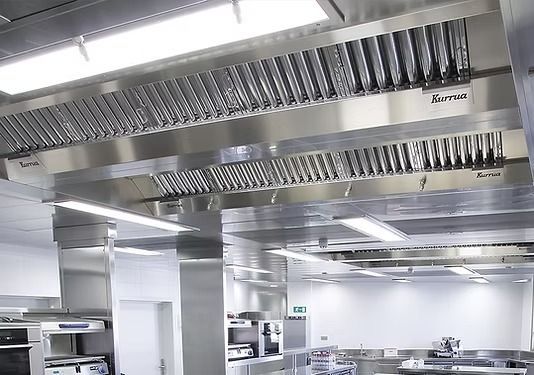 Una campana extractora de cocina comercial de acero inoxidable con filtros deflectores industriales instalada 