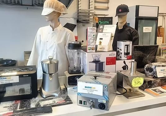 Dos maniquíes vestidos con uniformes de chef se encuentran detrás de un mostrador que exhibe diversos electrodomésticos