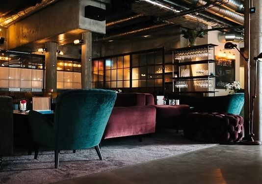 Un salón con iluminación tenue y ambiente íntimo, con sillones de terciopelo color turquesa