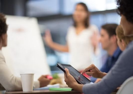 Un grupo de personas sentadas a una mesa con una tableta durante una reunión de negocios