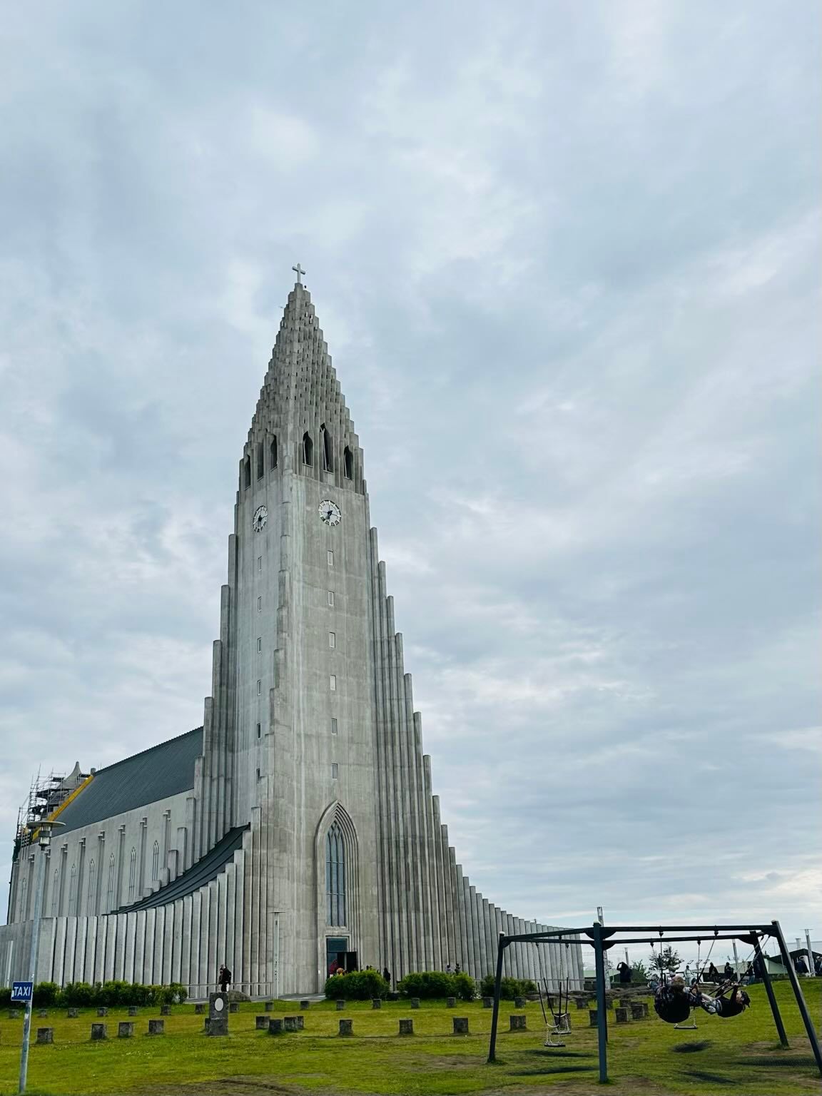 Hallgrímskirkja church in Reykjavík, Iceland, under cloudy sky. Tall, gray church with a pointed tower.