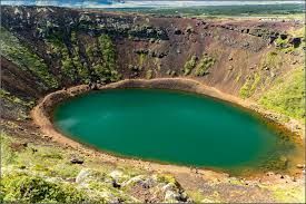 Crater lake with teal water surrounded by reddish-brown and green rocky walls in Iceland.