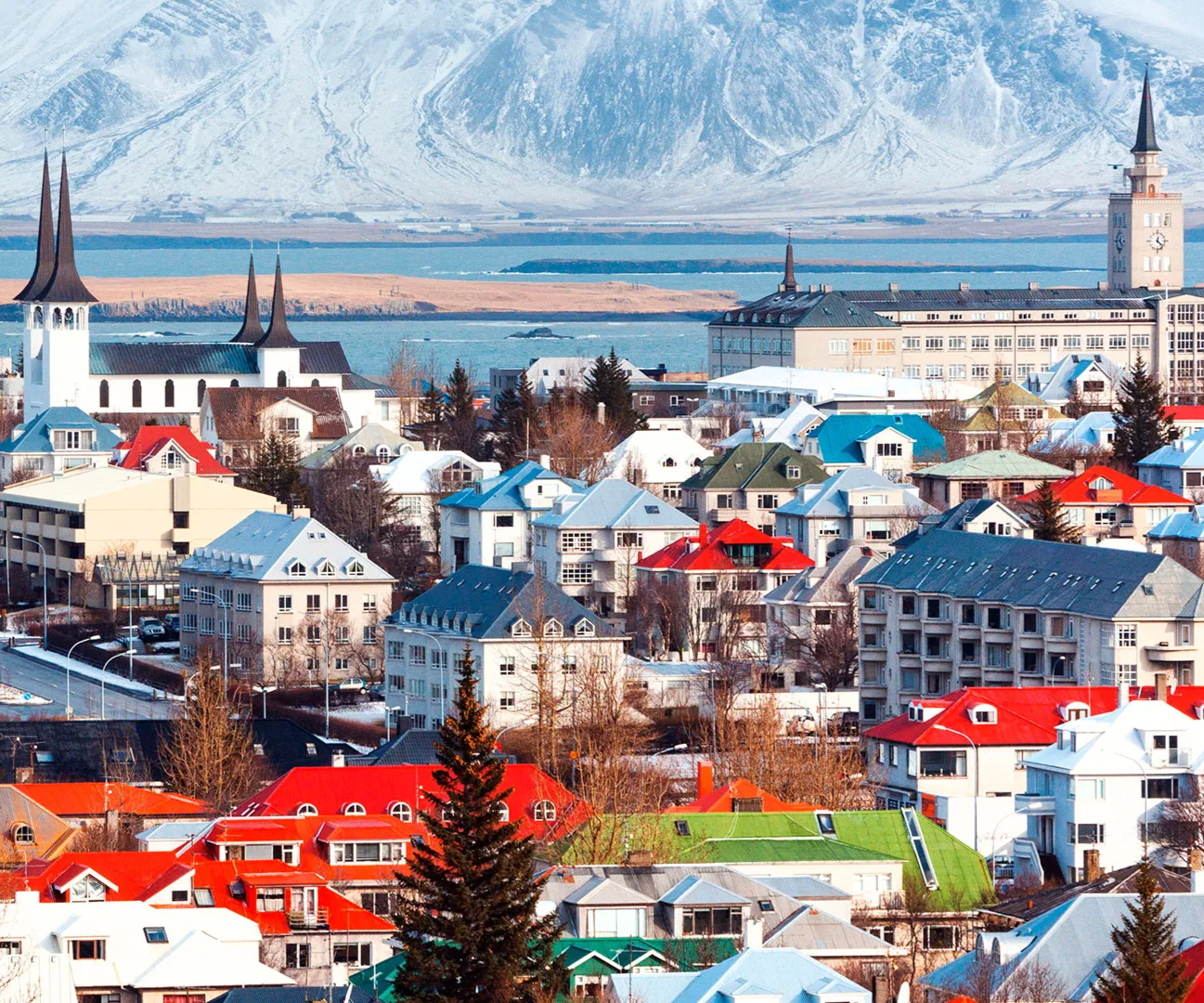 Waterfall cascading through a cave, orange-lit sky with blue clouds at sunset.