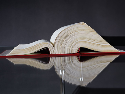 Livre ouvert aux pages crème sur une surface noire réfléchissante.