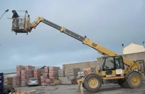 Un hombre está sentado en un cubo sobre una grúa que dice