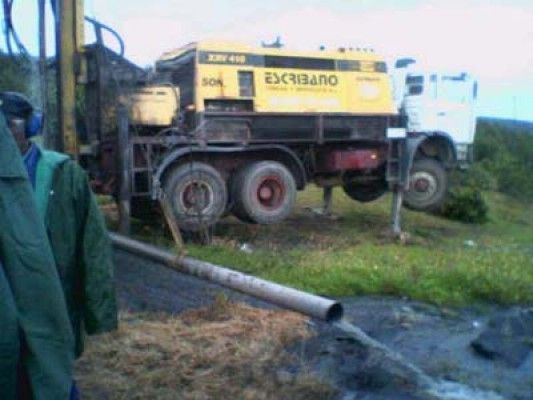 Un hombre con una chaqueta verde está parado frente a un camión que tiene escrito