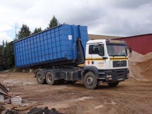 Un camión volquete azul está estacionado en un campo de tierra