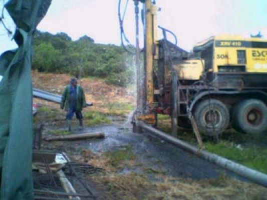 Un hombre está parado frente a una excavadora amarilla.