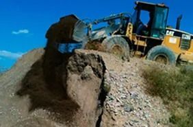 Una excavadora está moviendo tierra en la cima de una colina.