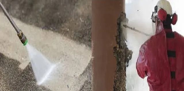 Un hombre con un traje rojo está rociando una tubería con una hidrolavadora.
