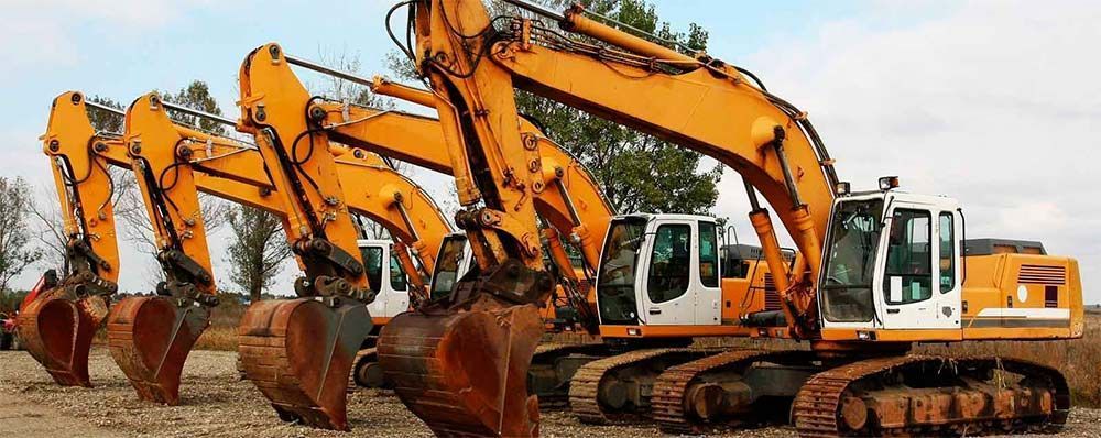 Una fila de excavadoras amarillas están estacionadas en un campo.