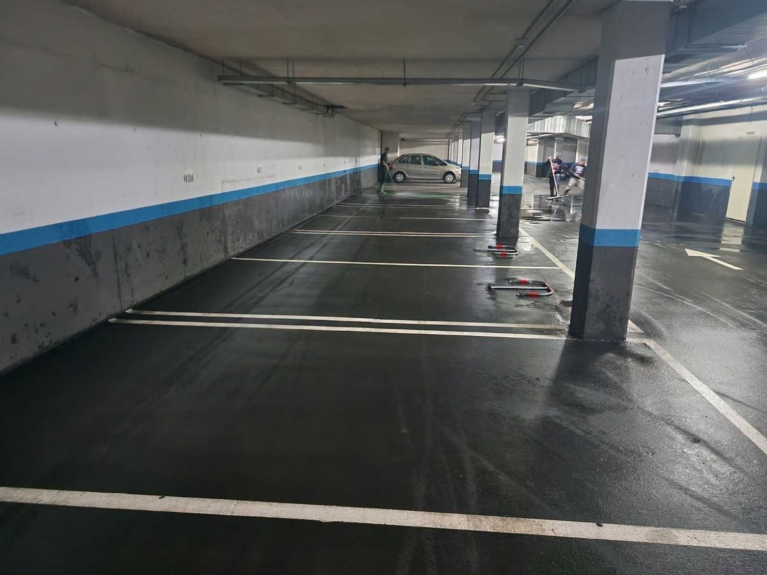 Garaje subterráneo vacío con el suelo mojado, paredes blancas y marcas azules en el suelo