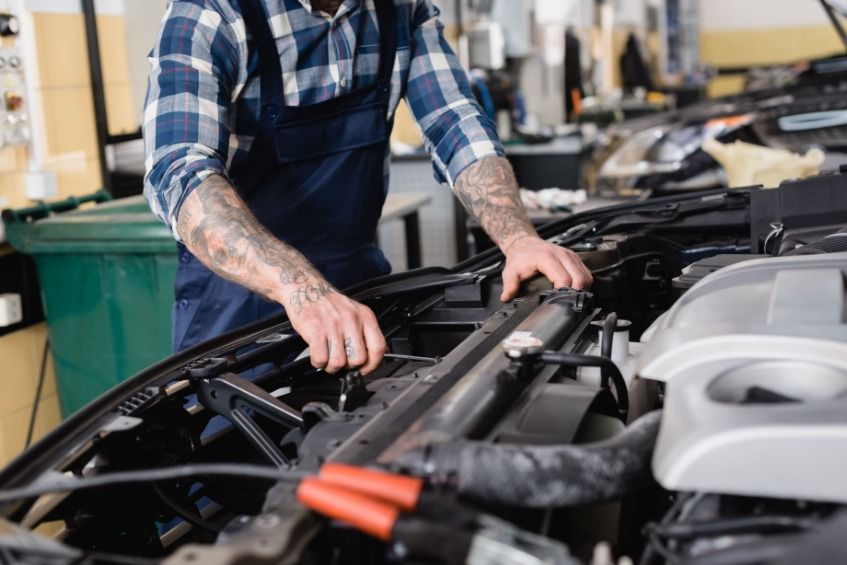 Un hombre está trabajando en el motor de un coche en un garaje.