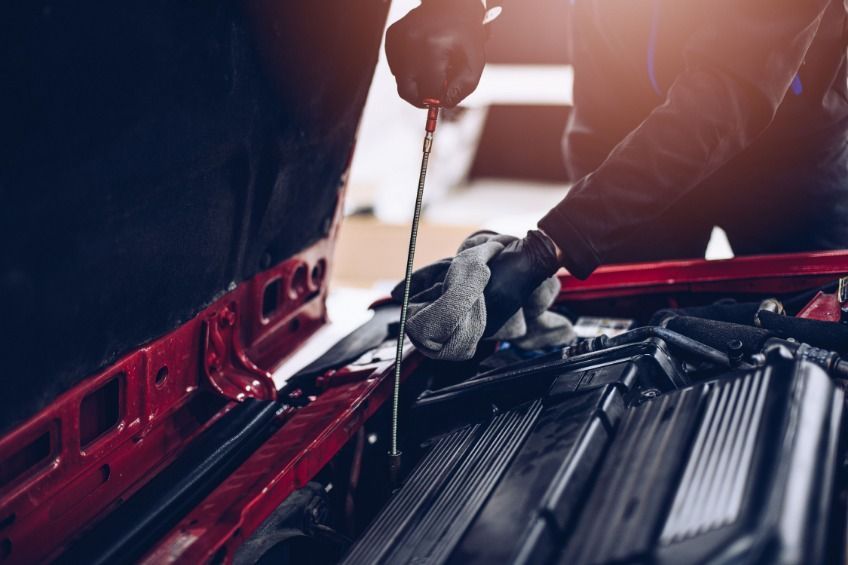 Un hombre está comprobando el nivel de aceite de un coche con una varilla de nivel.