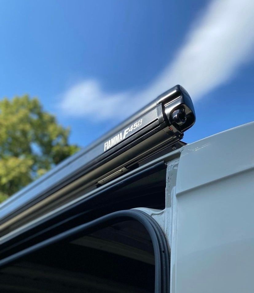 Una furgoneta blanca con un toldo negro encima.