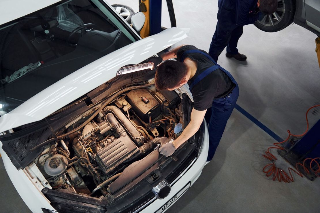 Un hombre está trabajando en el motor de un coche en un garaje.