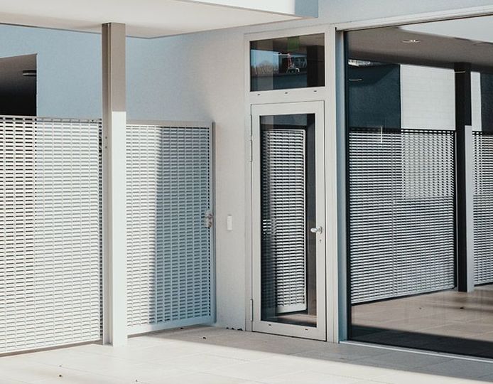 Patio moderne avec portes coulissantes en verre et panneaux d'intimité à motifs, baigné de lumière naturelle.